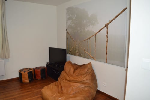 Gemütliches Wohnzimmer im Domaine Le Piboul mit beigem Sitzsack, TV, dekorativen Poufs und nebeliger Waldbrücken-Kunstwerk