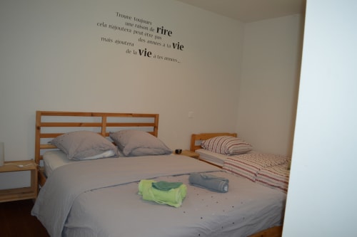 Helles Schlafzimmer im Domaine Le Piboul mit Holzbetten, grauer Bettwäsche und französischem Wandtext im Cottage Fontcouverte
