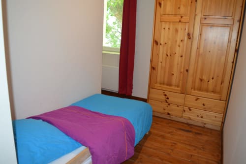 Schlafzimmer im Cottage Le Régisseur auf dem Domaine Le Piboul mit blauer Bettwäsche, hölzernem Kleiderschrank und Gartenblick
