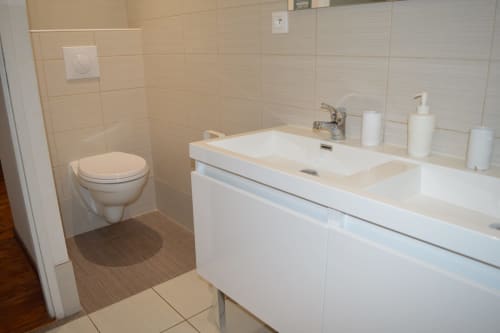 Modernes Badezimmer mit Doppelwaschtisch, Toilette und gefliesten Wänden im Ferienhaus Domaine Le Piboul in Fontcouverte