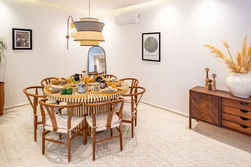 Salle à manger contemporaine aux Résidences et Hôtels M avec table ronde en bois, luminaires suspendus et mobilier années 50