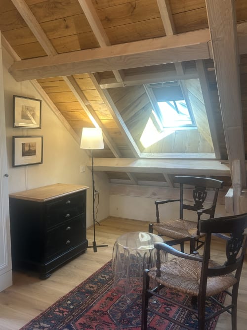 Chambre studio mansardée lumineuse à Cour Du Liège avec poutres apparentes, vérrières, bureau, commode noire et chaises tressées