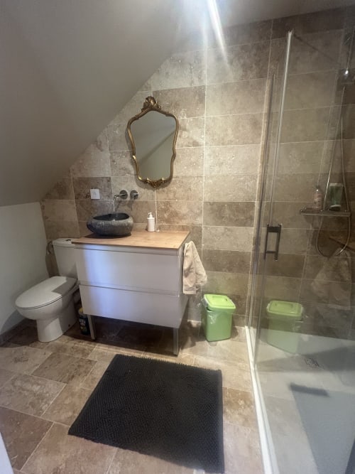 Salle de bain moderne du gîte Cour Du Liège avec vasque, toilettes, douche et élégant carrelage