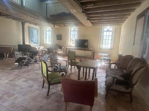 Spacieux hall de réception à la Cour Du Liège à Baugé-en-Anjou avec poutres en bois, sièges confortables, télévision et lumière naturelle