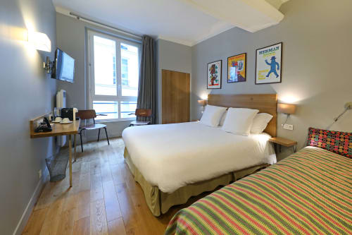 Chambre d'hôtel moderne à l'Hôtel Louvre Richelieu Paris avec deux lits, mobilier en bois et vue sur la ville