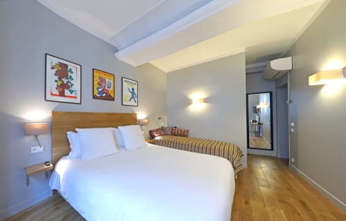 Chambre moderne de l'Hôtel Louvre Richelieu à Paris avec literie blanche, tête de lit en bois, parquet et décor coloré