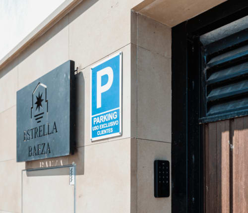 Entrada del hotel Estrella Baeza con señal de aparcamiento exclusivo para clientes y puerta de madera oscura en Baeza, España