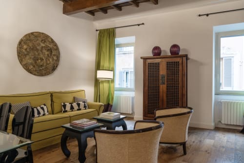 Elegante soggiorno presso Residenza Clodio a Roma con divano color senape, arredi in legno e vista sulla città