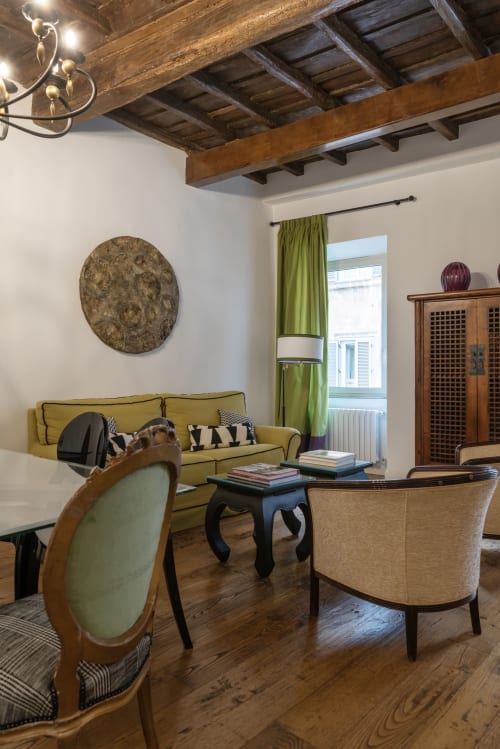 Elegante soggiorno presso l'appartamento Residenze Clodio a Roma con divano oliva, travi in legno, camino con arte e vista sulla città