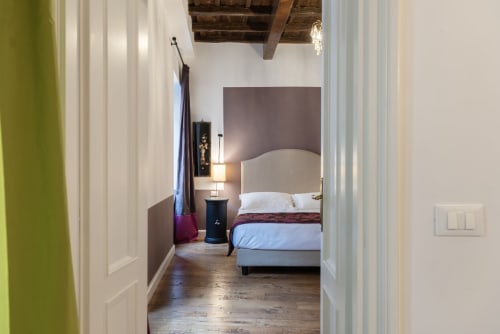 Camera moderna alle Residenze Clodio vicino gli Scalini di Spagna a Roma, con testata color crema, biancheria blu e travi a vista