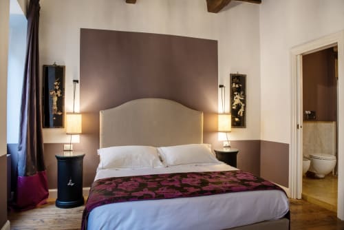 Elegante camera da letto presso Residenza Clodio vicino agli Spanish Steps, Roma, con testata in crema, plaid bordeaux, lampade comodino e bagno privato