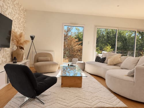 Séjour de villa moderne avec canapé beige incurvé, fauteuil noir et vue sur le jardin à Marcel Vacances à Banassac-Canilhac