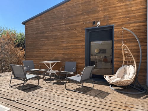 Terrasse en bois de la villa Marcel Vacances avec chaises longues, fauteuil suspendu et vue sur le jardin à Banassac-Canilhac