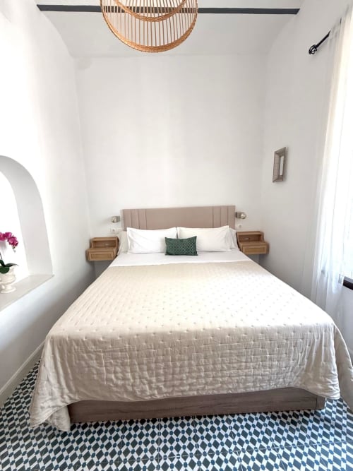 Dormitorio moderno en Casa Turística San Agustín de Córdoba con paredes blancas, cabecero tapizado en beige, mesitas de noche de madera