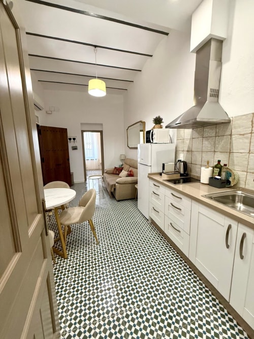 Cocina moderna y sala de estar en el Apartamento Deluxe de Casa Turística San Agustín, Córdoba con mueblería blanca y geométrica