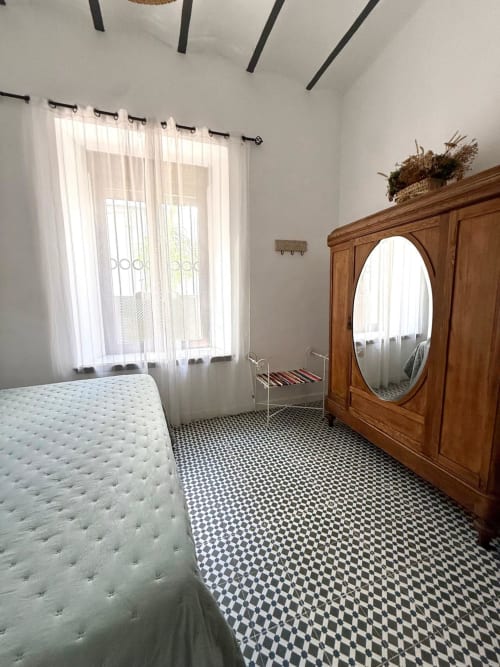 Dormitorio luminoso en Casa Turística San Agustín con cama blanca, armario de madera, piso a cuadros y vistas al jardín