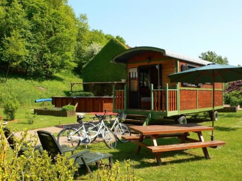 Roulotte au Relais de Maufront avec vélos, table de pique-nique et vue sur le jardin à Ouagne
