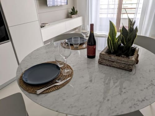 Tavolo da pranzo moderno con piano in marmo, coperto, bottiglia di vino e piante grasse in vaso nell'appartamento di Palermo