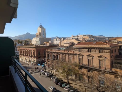 Vista dal balcone del BnB del Parlamento: centro storico di Palermo con architettura antica, montagne e grattacieli del downtown