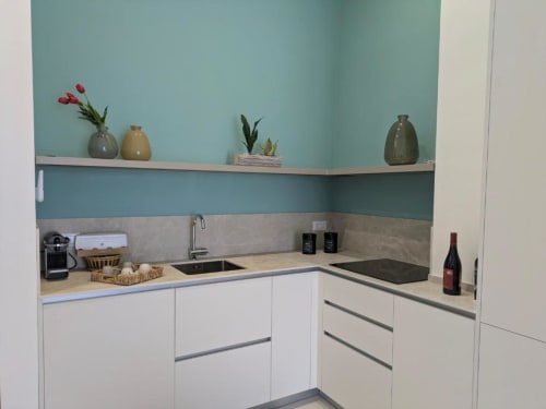 Piccola cucina moderna in appartamento a Palermo con mobili bianchi, parete azzurra, ripiani aperti con vasi decorativi e