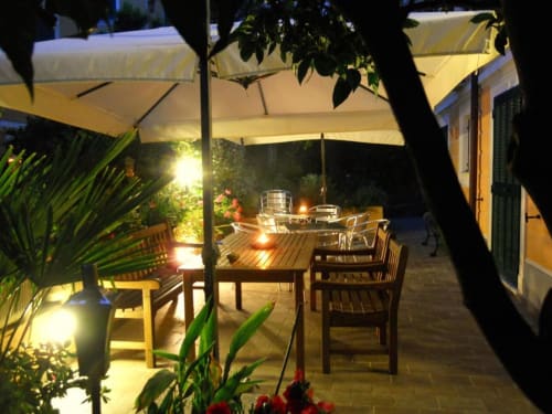 Elegante patio notturno dell'Hotel Villa Moderna a Genova con area ristorazione illuminata, ombrelloni, arredi in legno