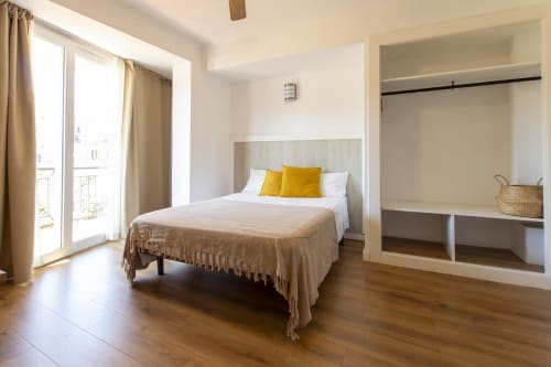 Dormitorio moderno en Loft 201 del hotel El Sol II, Tossa de Mar, con cama queen, almohadas amarillas, acceso a balcón y armarios empotrados