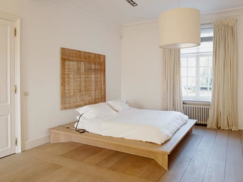Bright Bernard Suite bedroom at Castanea Business & Suites with wooden platform bed, cream pendant light, and garden views