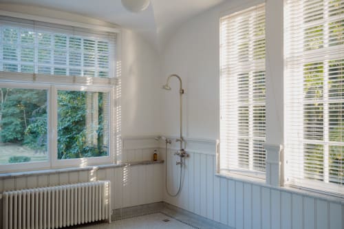 Bright bathroom in Bernard Suite at Castanea Business & Suites with garden views, white paneling, rainfall shower, and