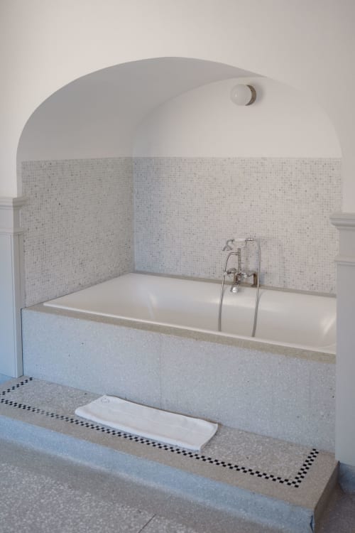 Modern bathroom with white bathtub, mosaic tile walls, and arched ceiling at Castanea Business & Suites in Merelbeke
