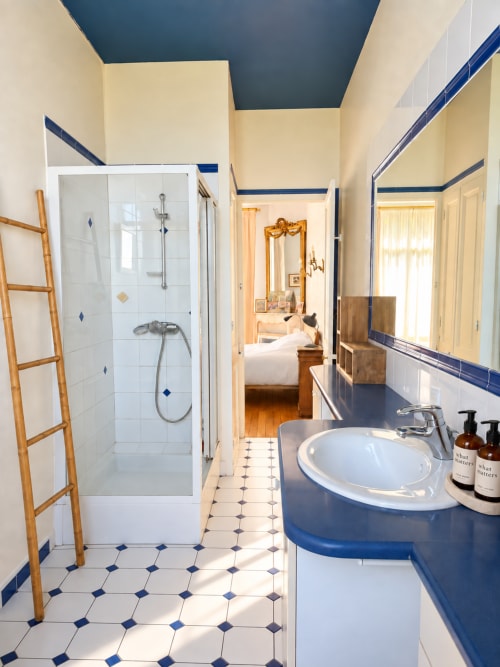 Salle de bain moderne à la villa ARLOÉ à La Rochelle avec accents bleus, lavabo blanc, douche à l'italienne et décoration en bois