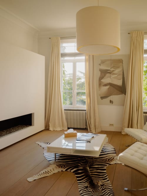 Modern sitting area in Bernard Suite at Castanea Business & Suites with cream pendant lamp, fireplace, and garden views
