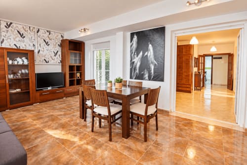 Zona de estar de la Suite Castelar en el hotel Living Sur de Sanlúcar de Barrameda, con muebles de madera, mesa de comedor y salón con televisión