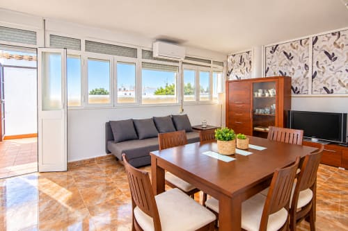 Sala de estar de la Suite Castelar en el hotel Living Sur de Sanlúcar de Barrameda con comedor, sofá y acceso a terraza