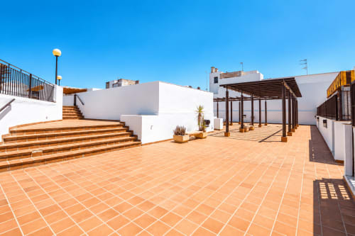 Terraza en la azotea del hotel Living Sur en Sanlúcar de Barrameda con baldosas de barro, edificios blancos, pérgola de madera y