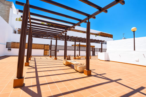 Terraza del apartamento Living Sur en Sanlúcar de Barrameda con pérgola de madera, tejas de barro y estilo andaluz blanco