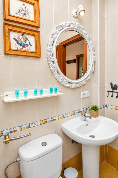 Elegante baño de la Suite Castelar en Living Sur, Sanlúcar de Barrameda, con lavabo de pedestal, espejo blanco ornamentado y