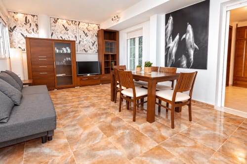 Zona de estar de la Suite Castelar en el hotel Living Sur de Sanlúcar de Barrameda con muebles de madera, mesa de comedor, sofá gris y
