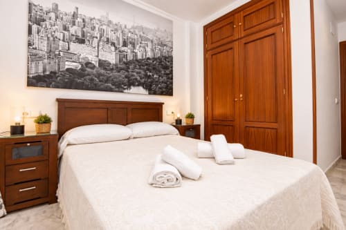 Habitación Castelar del hotel Living Sur en Sanlúcar de Barrameda con muebles de madera y obra de arte del horizonte urbano