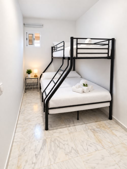 Literas de metal negro con ropa de cama blanca en la Suite Castelar de Living Sur, Sanlúcar de Barrameda