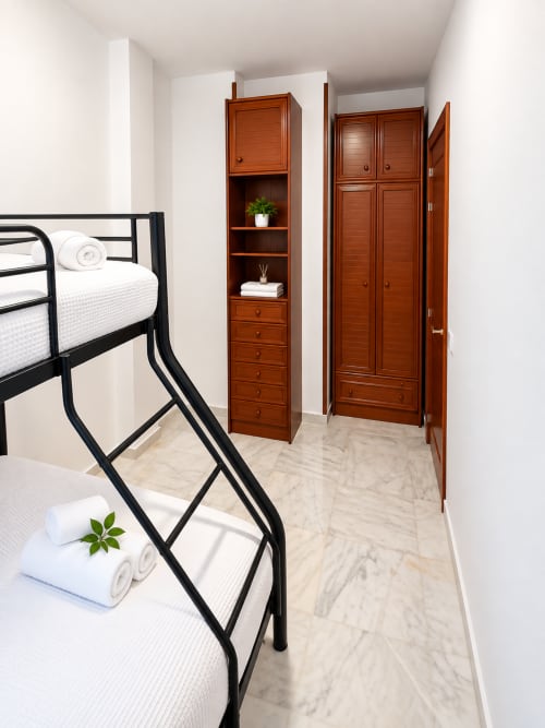 Literas modernas con ropa de cama blanca y almacenamiento de madera en la Suite Castelar de Living Sur, Sanlúcar de Barrameda