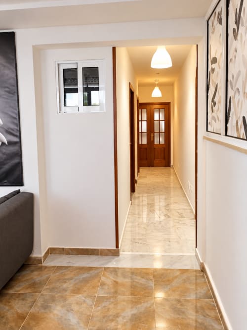 Pasillo moderno de la Suite Castelar en Living Sur, Sanlúcar de Barrameda, con suelos de mármol e iluminación colgante
