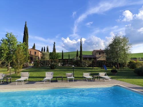 Piscina dell'Agriturismo Marinello a Pienza con lettini, cipressi e vista sulla campagna toscana