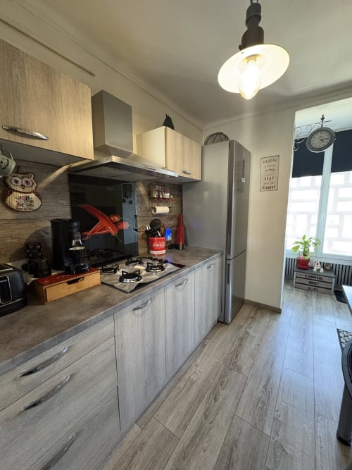 Cuisine moderne avec cuisinière à gaz, réfrigérateur en acier inoxydable et luminaires suspendus dans l'appartement Le Cocon Arlésien, Arles