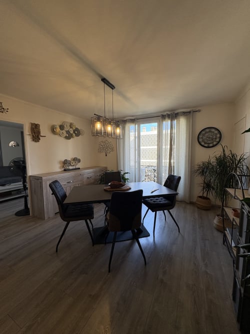 Salle à manger contemporaine de l'appartement Le Cocon Arlésien, Arles, avec table ronde, chaises noires, luminaires suspendus et vue sur la ville