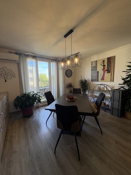 Salle à manger contemporaine avec vue sur la ville au Cocon Arlésien à Arles, table de repas, chaises noires et luminaires suspendus