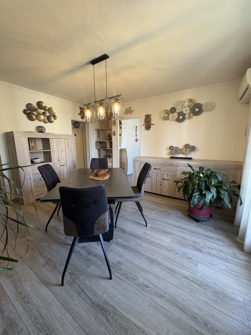 Salle à manger contemporaine de la Conciergerie Maurin à Arles avec chaises noires, table en bois, luminaires suspendus et mur décoratif