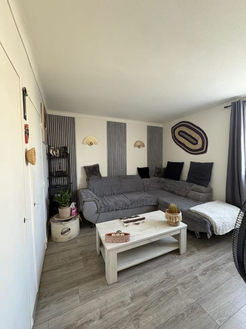 Studio accueillant à Arles avec canapé gris, table basse blanche, lit avec oreillers noirs et art mural décoratif