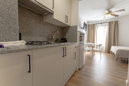 Cocina y sala de estar modernas en el Loft 305 del hotel El Sol II en Tossa de Mar, con muebles blancos y granito