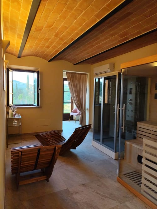 Spa dell'Agriturismo Marinello a Pienza con soffitto in legno, lettini relax e vista sulle montagne