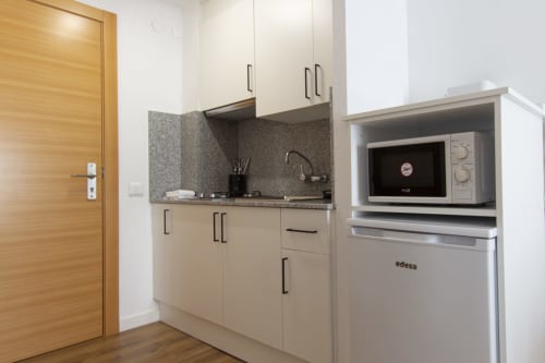 Cocineta moderna en Loft 305 del hotel El Sol II, Tossa de Mar, con muebles crema, encimera gris, microondas y